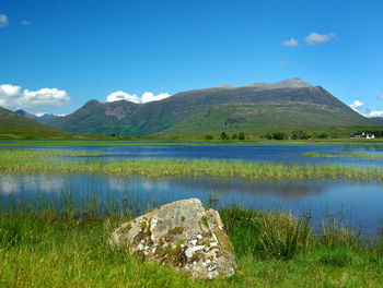 Scenic view of lake and mountains against blue sky