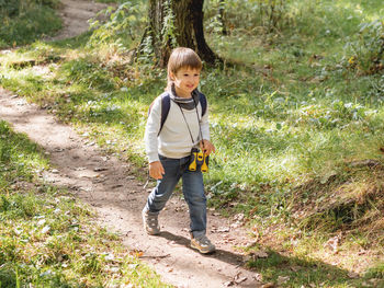 Curious boy is hiking in forest lit by sunlight. outdoor  activity for kids. child with binoculars