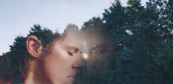 Portrait of woman looking away against trees