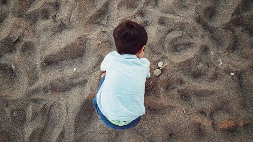 High angle view of boy bending on sand at beach