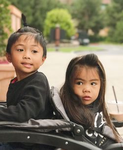 Siblings sitting on toy vehicle at park