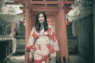 Portrait of young woman standing against building