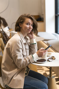 Young woman using mobile phone while sitting at home