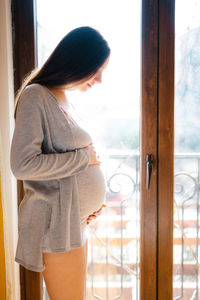 Side view of young woman looking through window