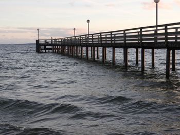 Pier over sea against sky during sunset