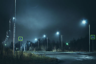 Illuminated road against sky at night