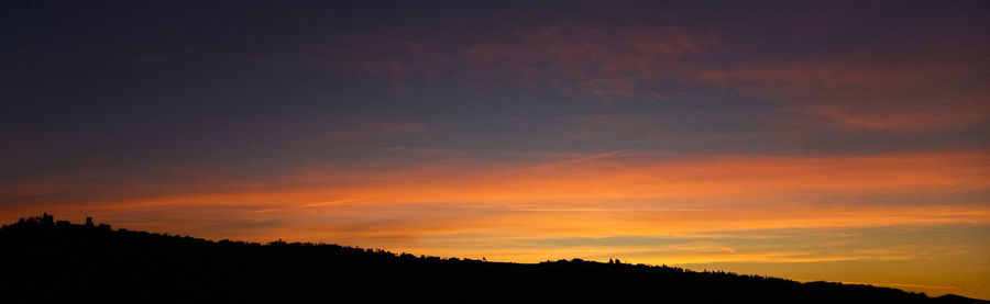 Silhouette trees against dramatic sky during sunset