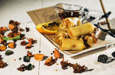 High angle view of spring rolls with sauce served in plate on table