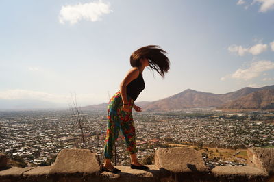 Woman looking at cityscape against sky