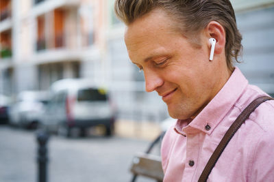 Moment of happiness - man with closed eyes enjoys listening to music on bench in bustling urban city