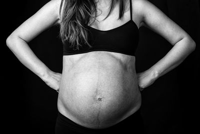 Midsection of woman standing against black background