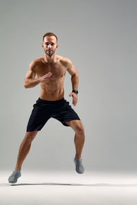 Portrait of shirtless man exercising against white background