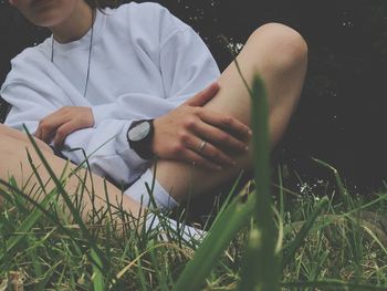 Midsection of woman sitting on grassy field