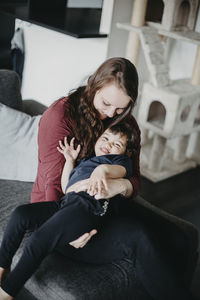 Full length of woman sitting on sofa at home
