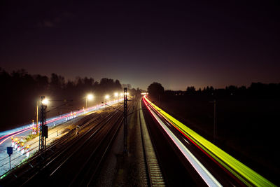 Light trails on railroad tracks against sky at night