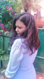 Young woman looking away while standing outdoors