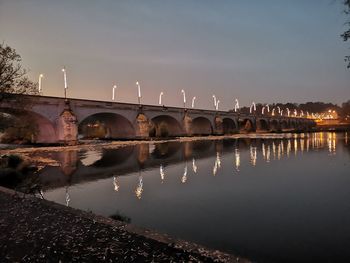 Bridge over river against sky at night