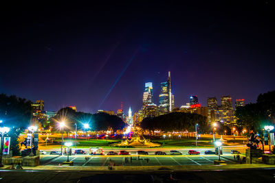 Illuminated street and buildings against sky at night