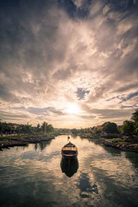 Boat in lake against sky during sunset