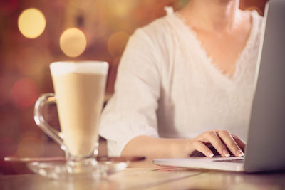 Close-up of woman using laptop on table