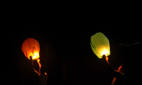 Low angle view of illuminated lighting equipment against black background