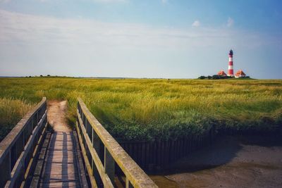 Scenic view of field by lighthouse against sky