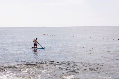 Man surfing on sea against clear sky