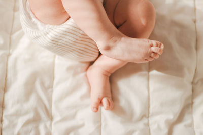 Low section of baby feet on bed at home