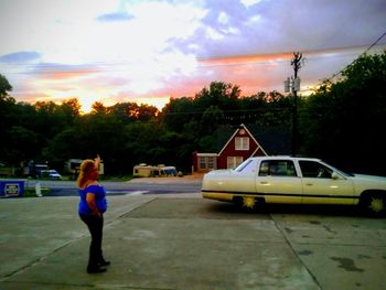 Woman on street against sky at sunset