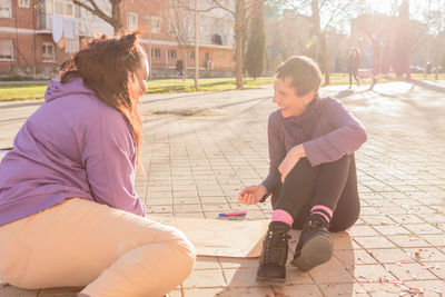 Smiling women with poster sitting on street