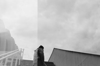 Low angle view of person standing by railing against sky