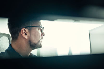 Side view of man looking through window