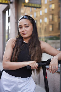 Portrait of young woman with electric scooter outdoors