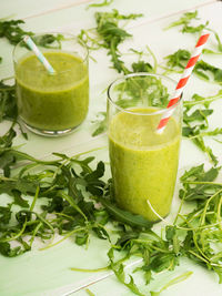 Smoothie in glasses and arugula on table