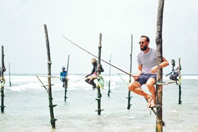 Man fishing in sea against sky