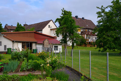 Houses by trees and building against sky