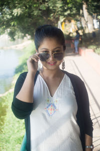 Portrait of young woman wearing sunglasses standing outdoors