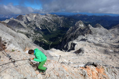Man climbing on rock against snowcapped mountains