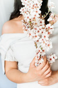 Midsection of woman holding white flowering plants