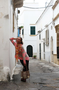 Woman standing in alley amidst buildings