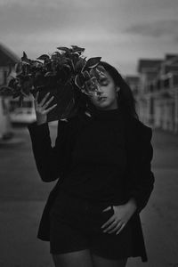 Young woman holding potted plant while walking in city