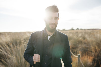 Portrait of mid adult man walking on field against sky