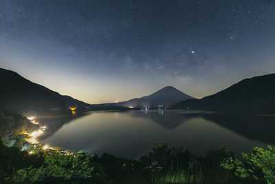 Scenic view of lake and mountains against sky at night