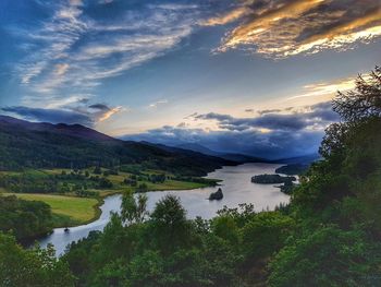 Scenic view of river by mountains against sky