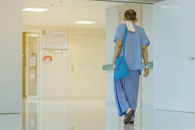 Rear view of man walking in corridor of building