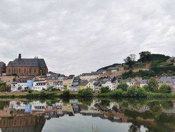 Town by lake and buildings in city against sky