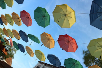 Low angle view of multi colored umbrellas against blue sky