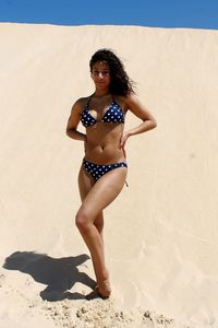 Portrait of young woman in bikini standing on beach