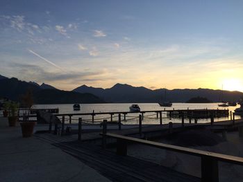 Boats sailing in river by mountains against sky during sunset