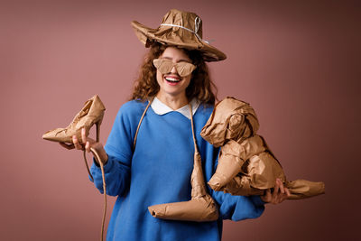 Portrait of woman wearing hat standing against yellow background